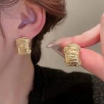 Сережки у вигляді розплавленого металу та маленьких хвиль золото на вусі