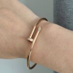 Тонкий браслет-цвях Cartier з камінням цирконію на кінцях з логотипом рожеве золото на руці