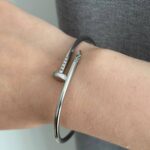 Тонкий браслет-цвях Cartier з камінням цирконію на кінцях з логотипом срібло на руці