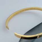Тонкий жорсткий браслет Cartier з камінням та логотипом лимонне золото лого