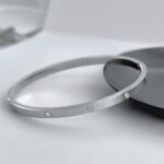 Тонкий жорсткий браслет Cartier з камінням та логотипом срібло