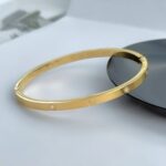 Тонкий жорсткий браслет Cartier з камінням та логотипом лимонне золото