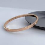 Тонкий жорсткий браслет Cartier з камінням та логотипом рожеве золото