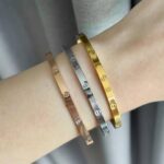 Тонкий жорсткий браслет Cartier з логотипом на руці
