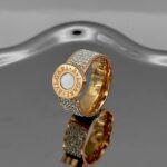 Широка каблучка BVLGARI з круглим логотипом та камінням золото білий1