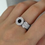Широка каблучка BVLGARI з круглим логотипом та камінням срібло чорний на руці