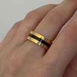 Каблучка BVLGARI з чорною серцевиною та логотипом лимонне золото на руці