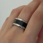 Широка каблучка BVLGARI з чорною серцевиною та логотипом срібло на руці