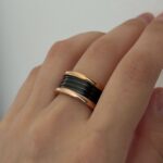 Широка каблучка BVLGARI з чорною серцевиною та логотипом золото на руці