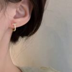 Мінімалістичні сережки з камінням з колекції Tiffany T золото на вусі
