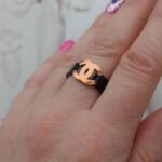 Чорна каблучка Chanel з логотипом рожеве на руці