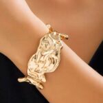 Широкий жорсткий браслет у вигляді виплавленого металу золото на руці
