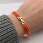 Вишуканий жорсткий браслет Hermes з логотипом у золоті помаранчевий на руці