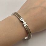 Вишуканий жорсткий браслет Hermes з логотипом у сріблі бежевий на руці