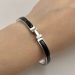 Вишуканий жорсткий браслет Hermes з логотипом у сріблі чорний на руці