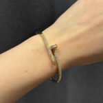 Тонкий жорсткий браслет-цвях Cartier у камінні золото на руці