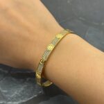 Жорсткий браслет Cartier у камінні з логотипом лимонне золото на руці