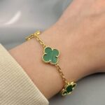 Класичний браслет Van Cleef з зеленими вставками та логотипом золото на руці