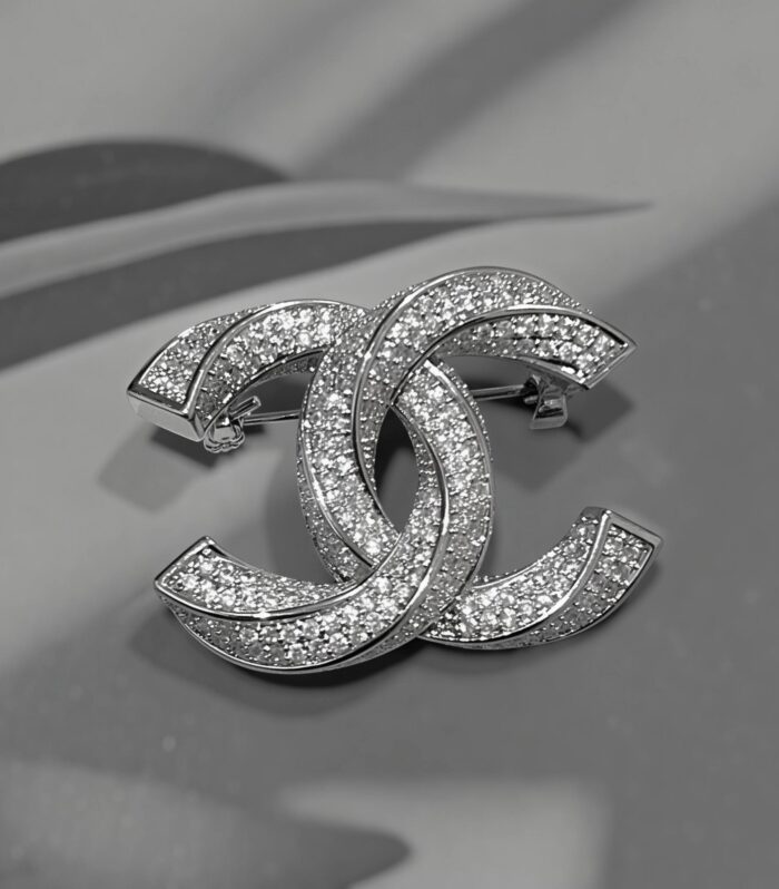Сяюча брошка Chanel у вигляді скрученого логотипу